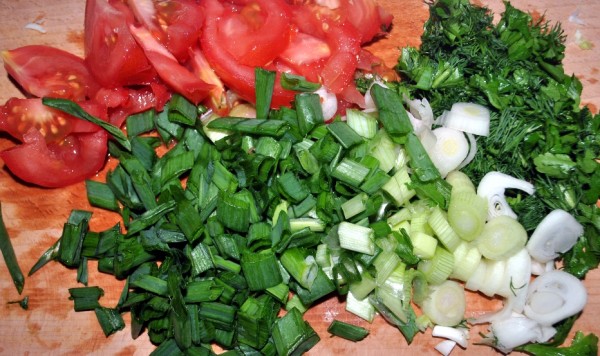 Нарезаем помидоры, лук, петрушку и укроп для овощного салата из капусты, помидор, зеленого лука, кукурузы и семечек кунжута